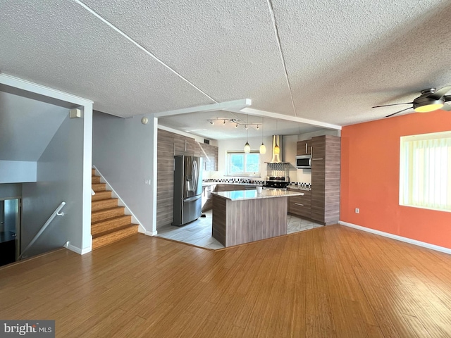 kitchen featuring stainless steel appliances, light wood-type flooring, modern cabinets, and a textured ceiling