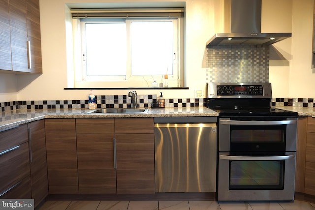 kitchen featuring appliances with stainless steel finishes, wall chimney exhaust hood, a sink, backsplash, and modern cabinets