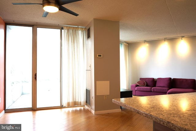 living room with track lighting, wood finished floors, a ceiling fan, baseboards, and a textured ceiling