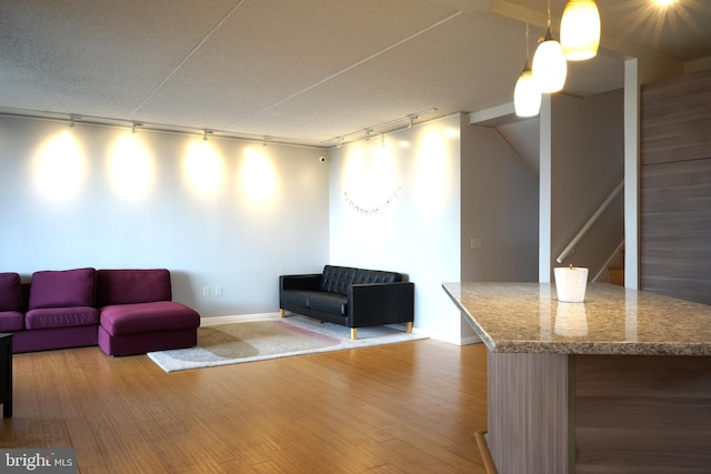 living room with track lighting, wood finished floors, stairs, and baseboards