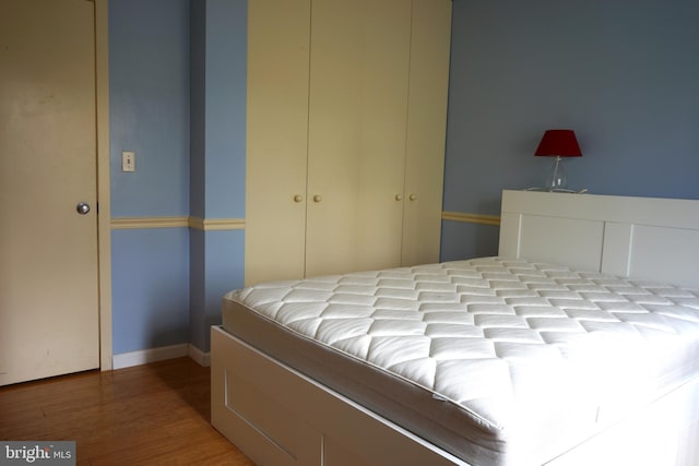 bedroom with wood finished floors, a closet, and baseboards