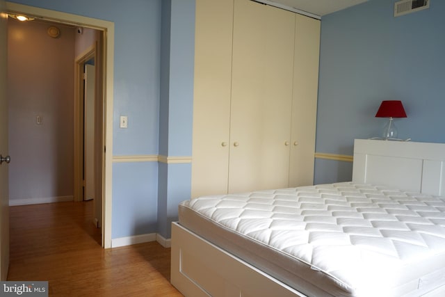 bedroom with a closet, wood finished floors, and baseboards