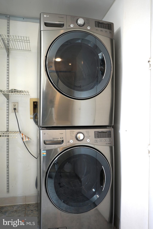 laundry room with stacked washer and clothes dryer and tile patterned flooring