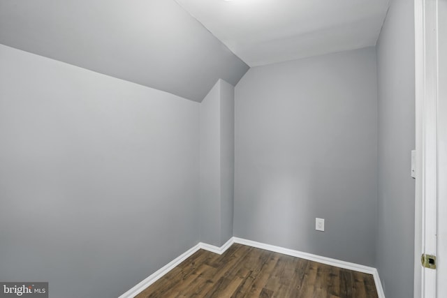 additional living space featuring dark wood-style flooring, baseboards, and vaulted ceiling