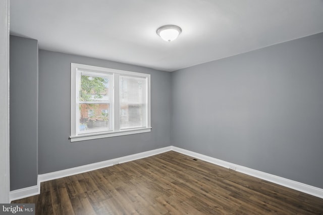 spare room featuring dark wood finished floors and baseboards