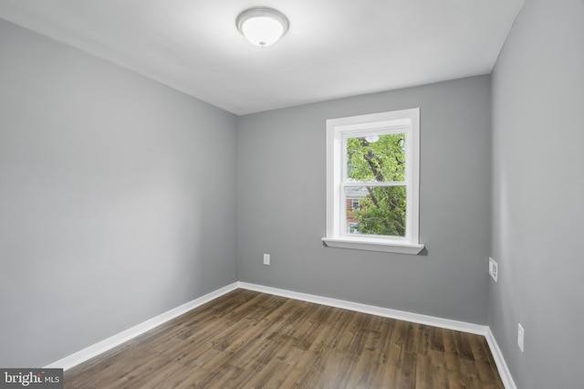 unfurnished room with dark wood-type flooring and baseboards
