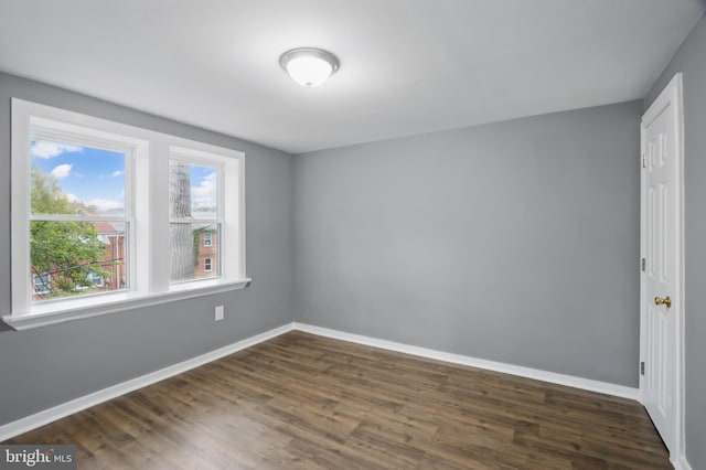 unfurnished room featuring dark wood-type flooring and baseboards