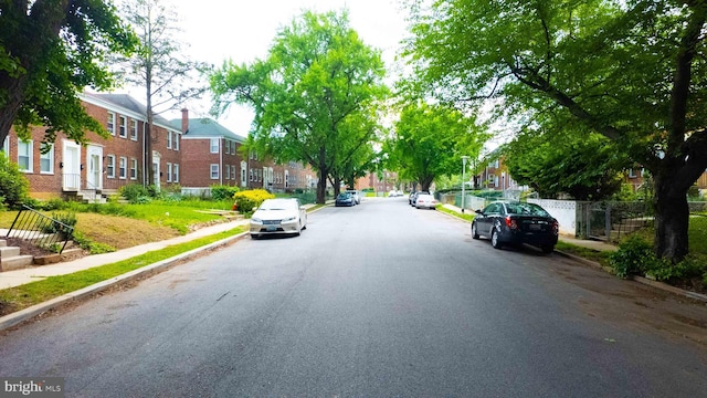 view of asphalt street featuring sidewalks, a residential view, and curbs