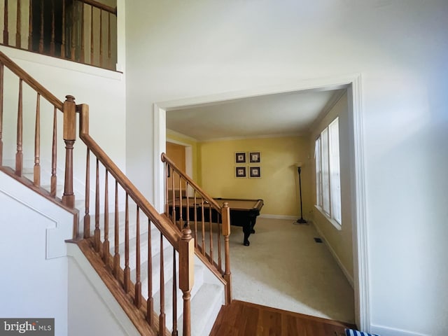 stairway featuring baseboards, crown molding, carpet flooring, and wood finished floors