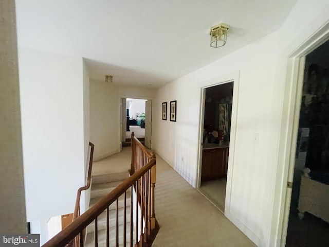 hallway with light carpet and an upstairs landing