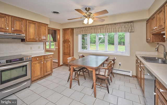 kitchen with appliances with stainless steel finishes, under cabinet range hood, a sink, baseboard heating, and brown cabinetry