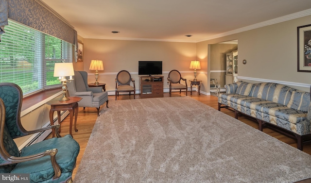 living area with wood finished floors, crown molding, baseboard heating, baseboards, and a baseboard heating unit