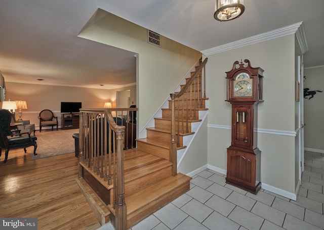 stairway with crown molding, a chandelier, baseboards, and tile patterned floors