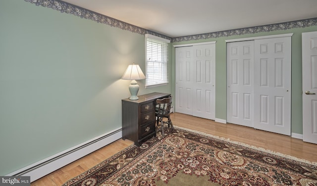 office with a baseboard heating unit, wood finished floors, and baseboards