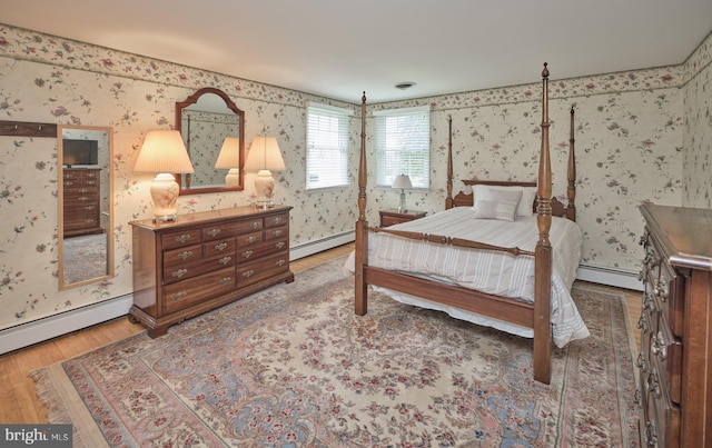 bedroom with wallpapered walls, a baseboard radiator, and wood finished floors