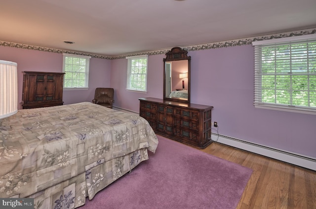 bedroom with wood finished floors and baseboard heating