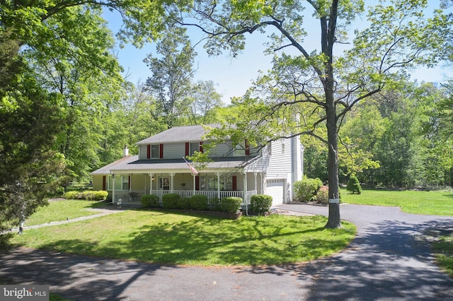 view of front of property featuring covered porch, driveway, a garage, and a front lawn