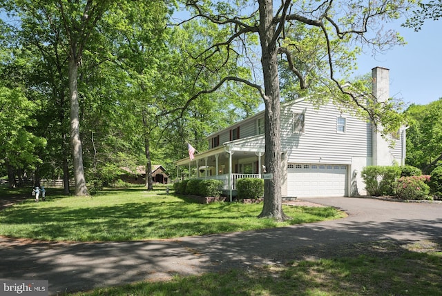 view of home's exterior featuring driveway, an attached garage, a yard, and a chimney