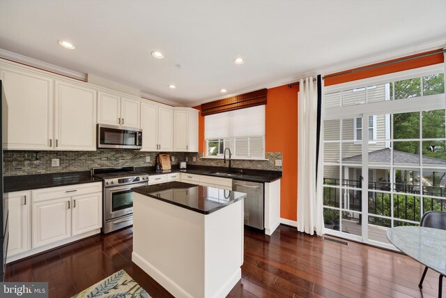 kitchen featuring appliances with stainless steel finishes, a sink, decorative backsplash, white cabinetry, and dark wood-style flooring
