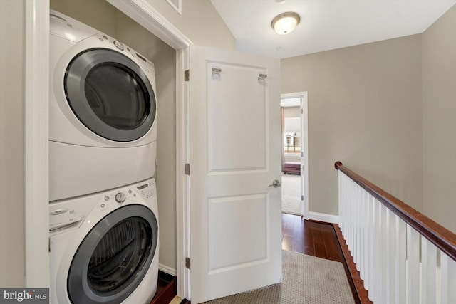 laundry room featuring estacked washer and dryer, dark wood finished floors, and baseboards