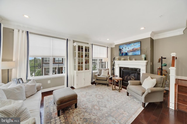 living area with crown molding, wood finished floors, a glass covered fireplace, recessed lighting, and baseboards