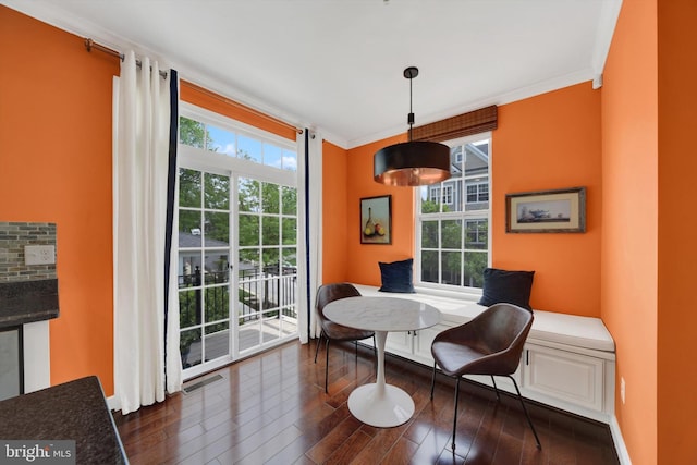dining space with dark wood finished floors and crown molding