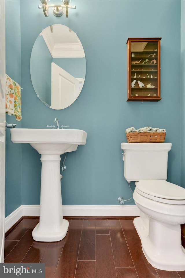 bathroom featuring baseboards, wood finished floors, and toilet