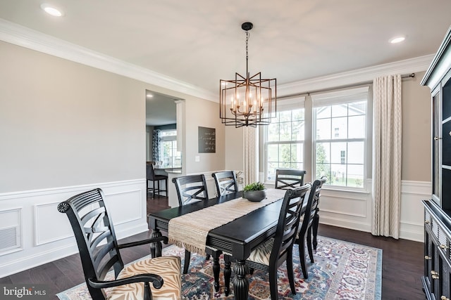 dining area with a chandelier, dark wood-style flooring, crown molding, wainscoting, and a decorative wall