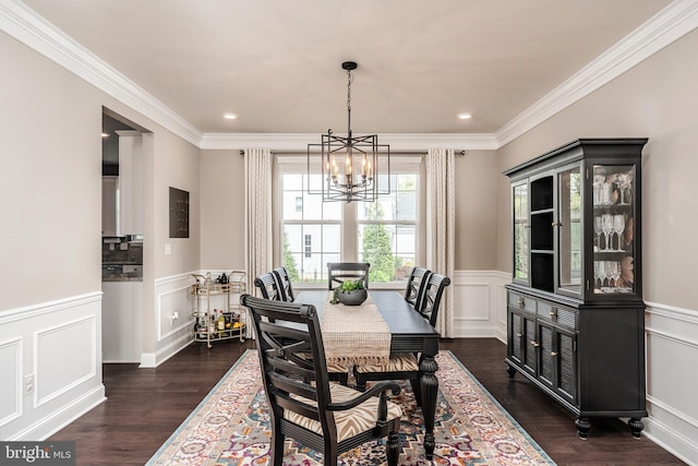 dining room featuring a chandelier, dark wood-style floors, a wainscoted wall, crown molding, and a decorative wall