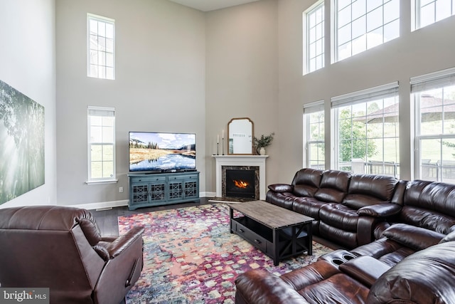 living room with a towering ceiling, wood finished floors, baseboards, and a fireplace