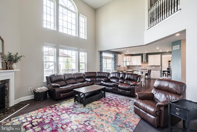 living area featuring dark wood-style flooring, a high end fireplace, a high ceiling, baseboards, and recessed lighting