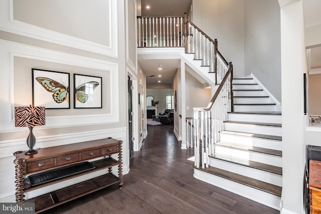 entryway with stairway, dark wood finished floors, and a high ceiling