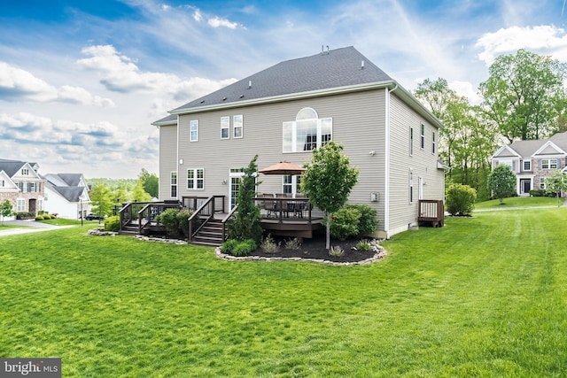 rear view of property featuring a yard and a wooden deck