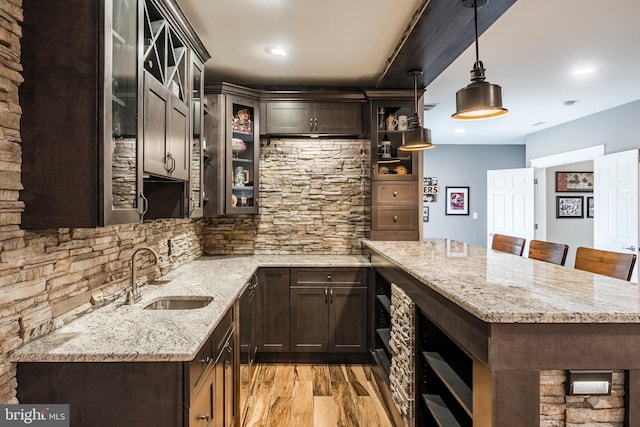 kitchen with a sink, a peninsula, dark brown cabinetry, light wood finished floors, and recessed lighting