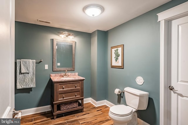 bathroom with wood finished floors, baseboards, toilet, and vanity