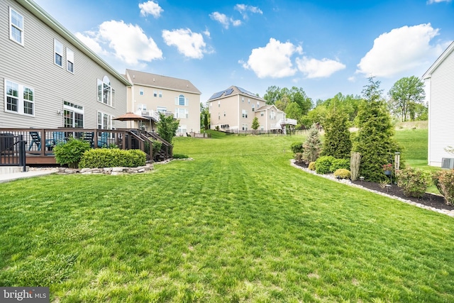 view of green lawn featuring a residential view and a wooden deck