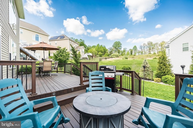 wooden terrace featuring outdoor dining space, a lawn, and grilling area