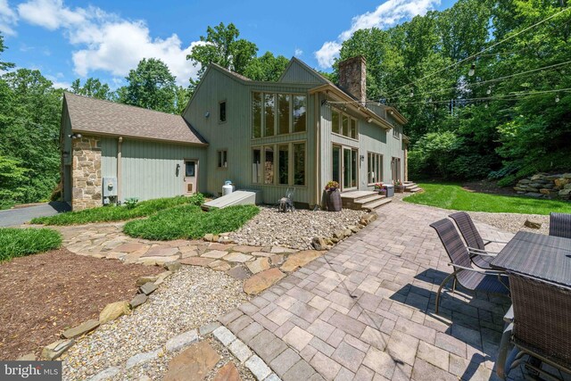 18 Beethoven Dr, Wilmington, DE 19807 - rear view of property featuring a patio, a chimney, stone siding, and roof with shingles