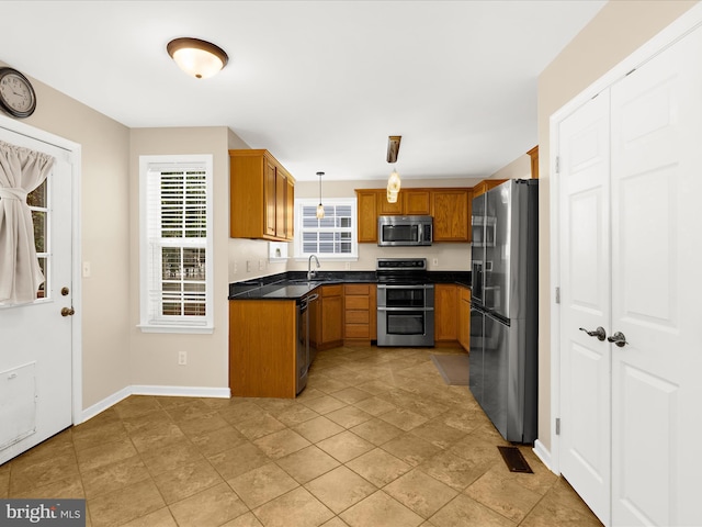 1904 Artillery Ln, Odenton, MD 21113 - kitchen featuring appliances with stainless steel finishes, dark countertops, brown cabinets, hanging light fixtures, and a sink