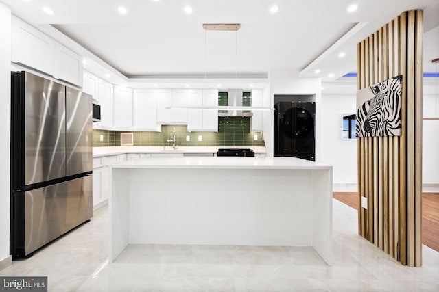 kitchen featuring appliances with stainless steel finishes, washer / dryer, white cabinetry, light countertops, and decorative backsplash