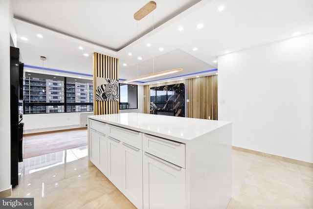 kitchen with light marble finish flooring, white cabinets, recessed lighting, a kitchen island, and hanging light fixtures
