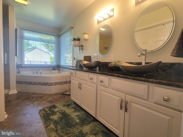 full bathroom featuring a garden tub, double vanity, and stone finish flooring