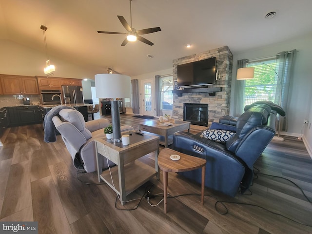 living area with a fireplace, lofted ceiling, a ceiling fan, and dark wood finished floors