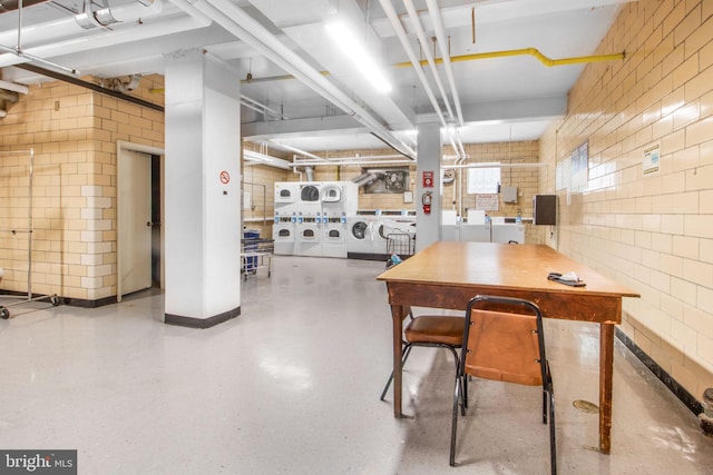 dining space featuring washer and clothes dryer, stacked washer / drying machine, a workshop area, and tile walls