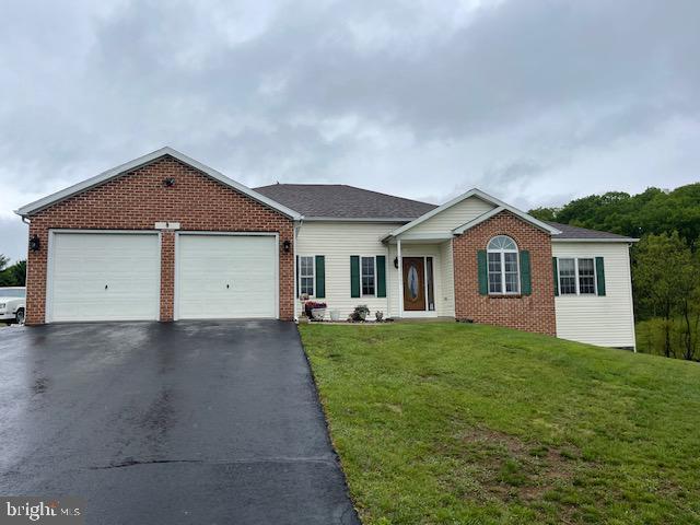 ranch-style house with asphalt driveway, an attached garage, brick siding, and a front yard
