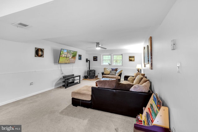 living room with a wood stove, carpet, and a ceiling fan