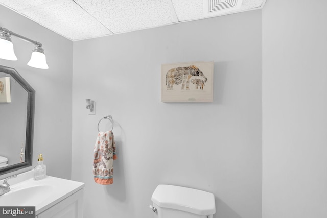 bathroom featuring a paneled ceiling, toilet, and vanity