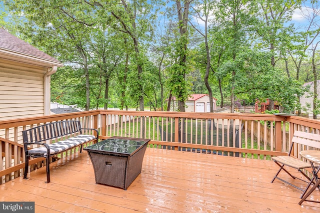 deck with an outbuilding, a storage unit, an outdoor living space, and view of scattered trees