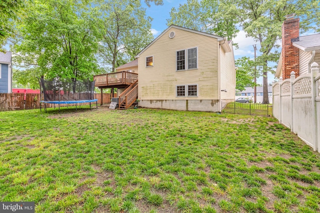back of house with a trampoline, a wooden deck, and stairs