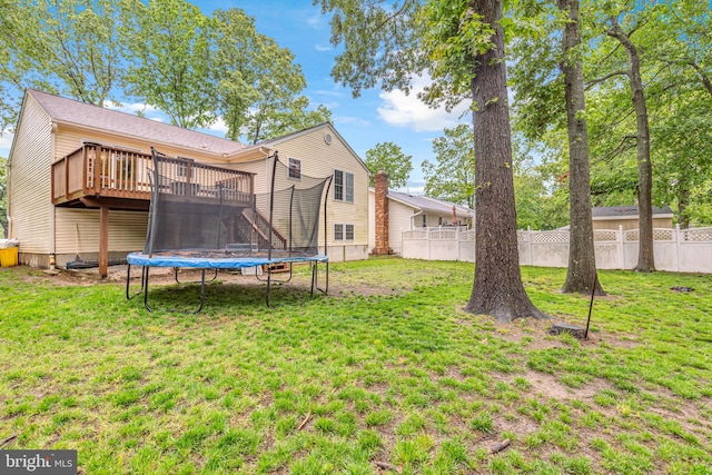rear view of property with a wooden deck, a trampoline, and stairway